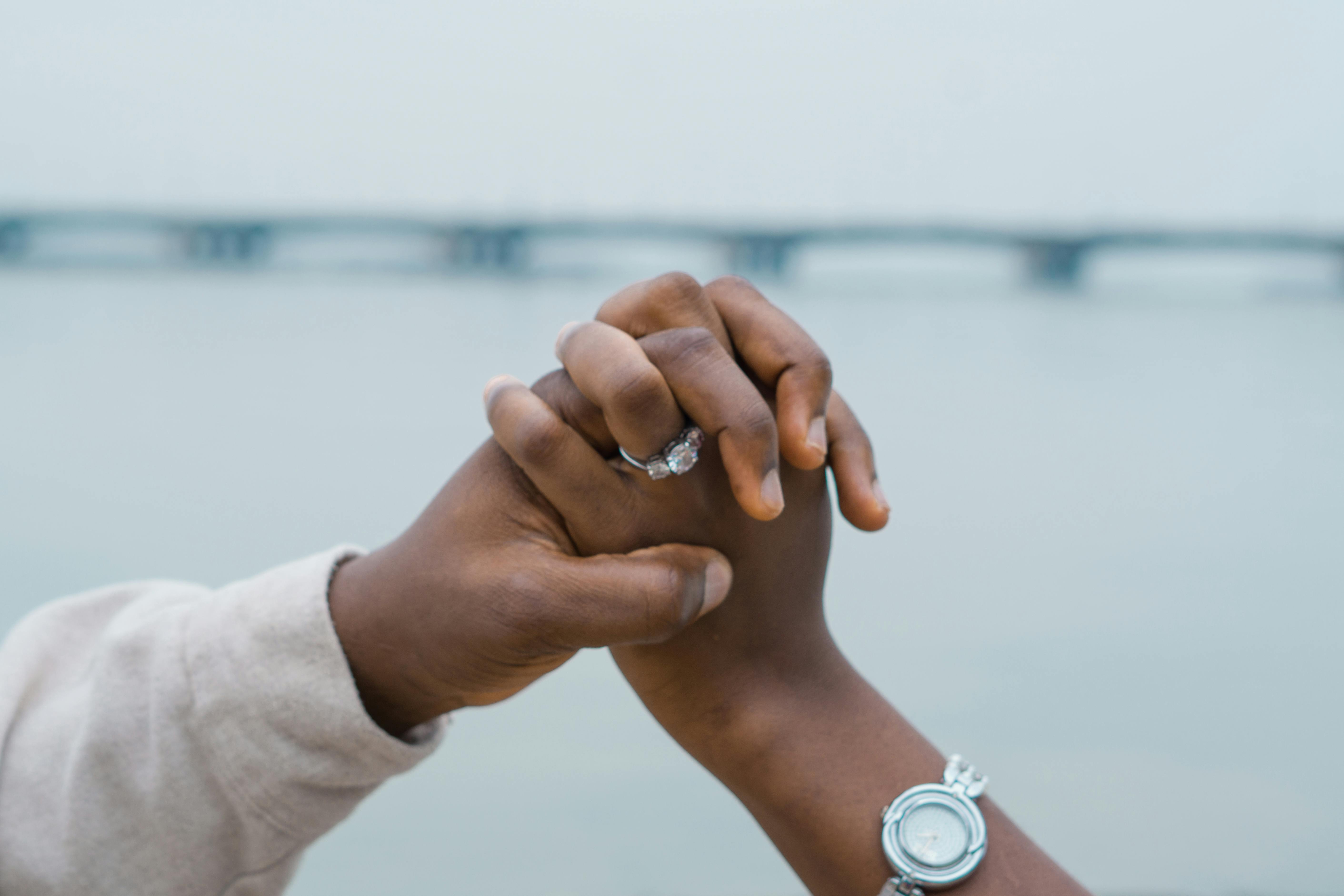 A couple holds hands with engagement ring visible over the bridge in Lagos, Nigeria.