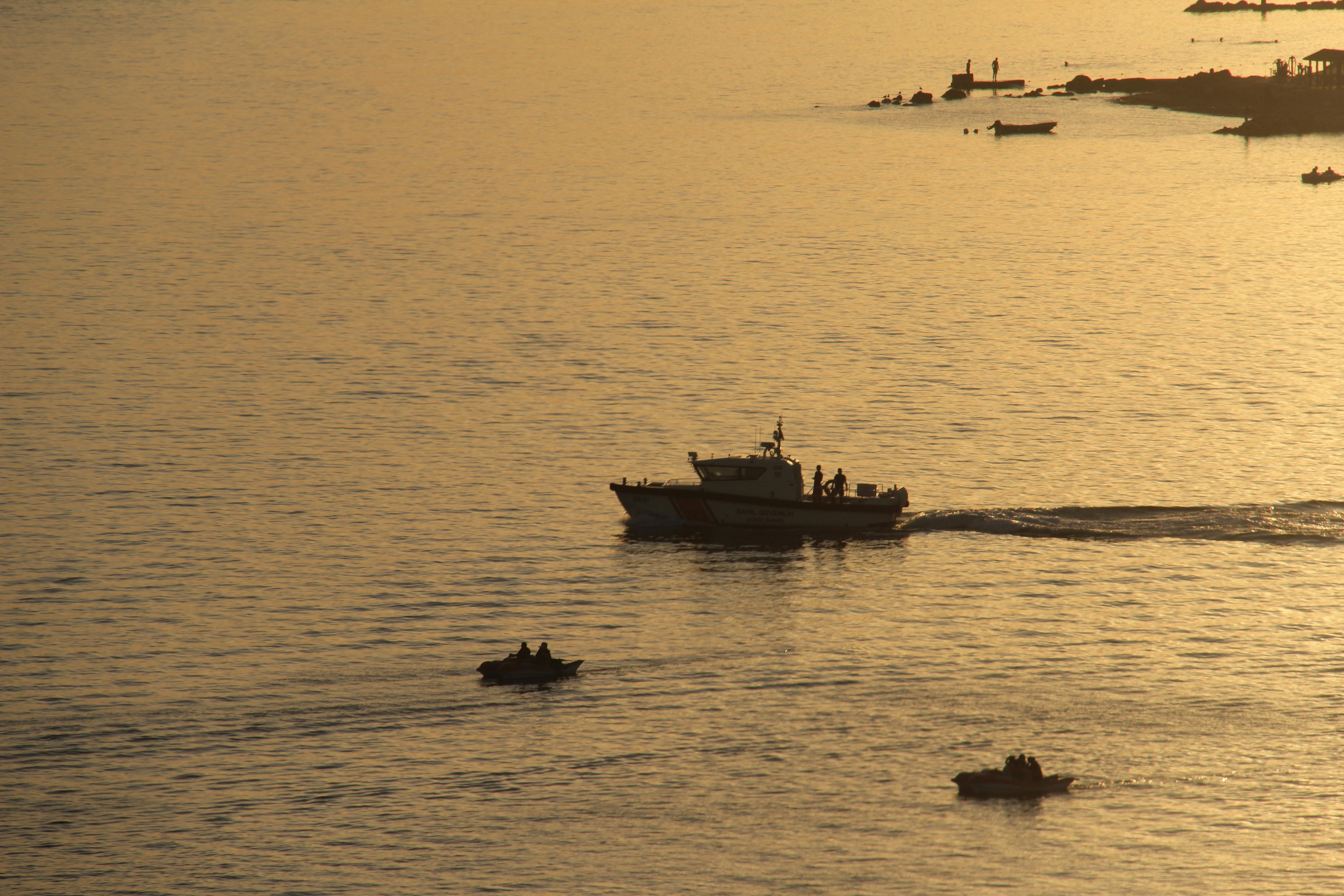 Boats silhouetted against a tranquil sunset sea reflecting warm golden hues.