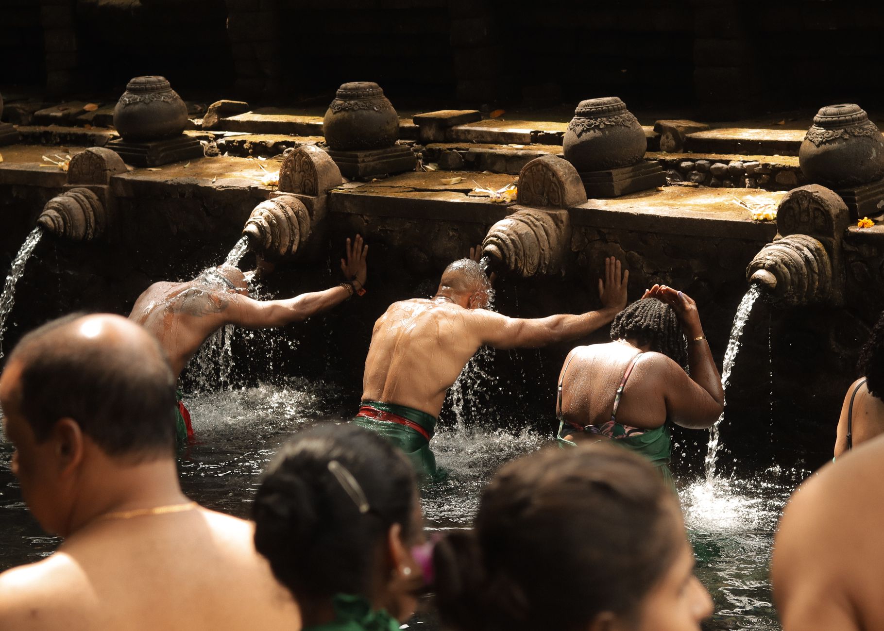 People engage in a traditional water purification ritual at a sacred site, symbolizing spiritual cleansing.