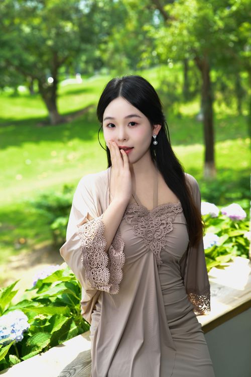 Free Young woman in elegant dress posing outdoors in a lush green garden. Stock Photo