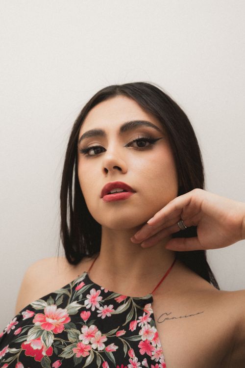 Free Close-up portrait of a woman with floral attire, looking elegantly at the camera. Stock Photo