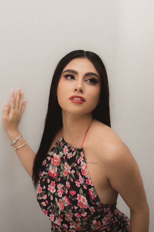 Free A stylish woman poses indoors wearing a floral dress, exuding elegance and confidence. Stock Photo