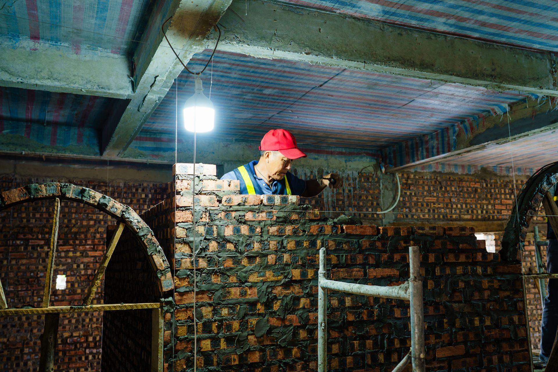 Skilled bricklayer building a wall at an indoor construction site in Hải Phòng, Vietnam.