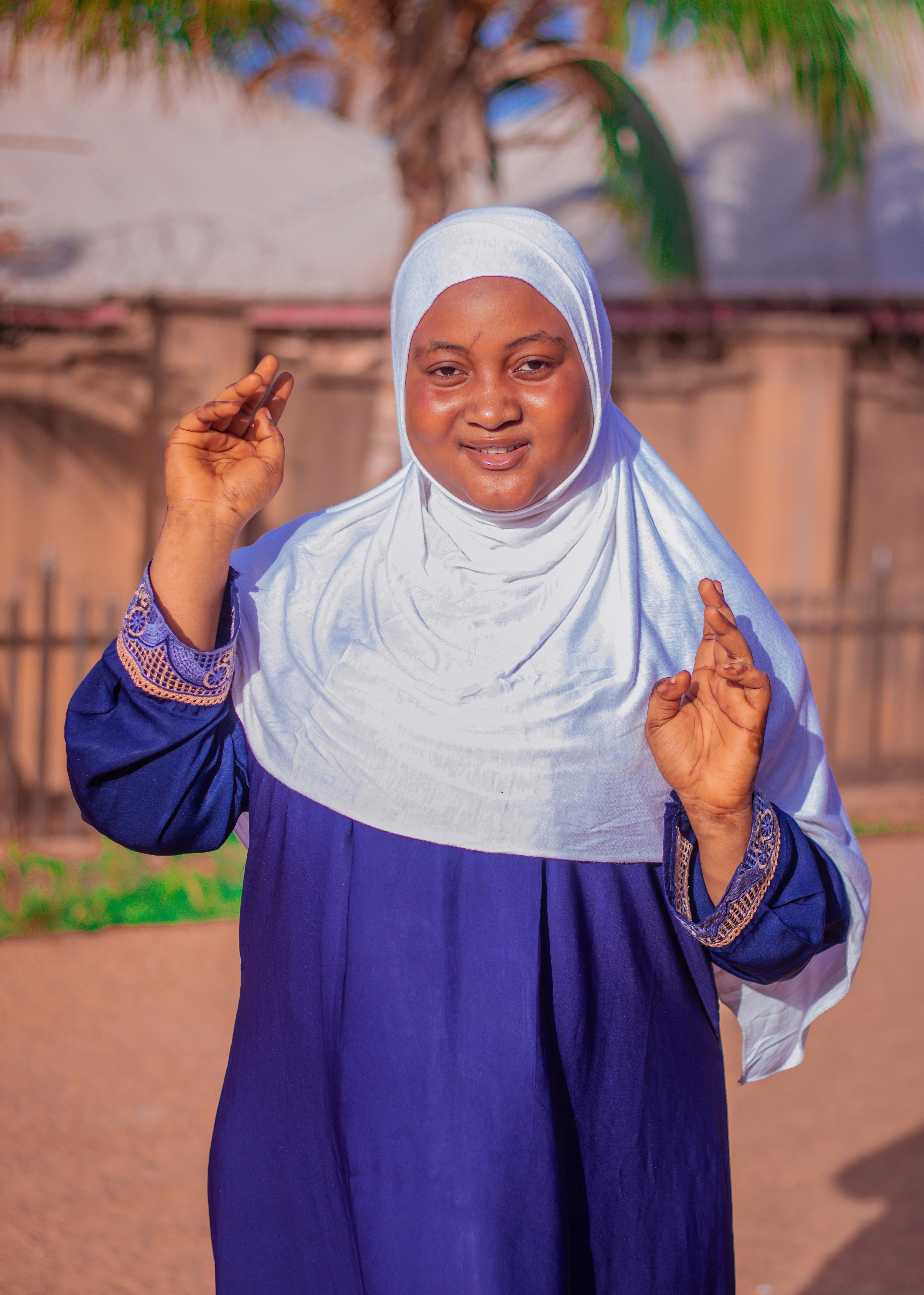 Smiling woman wearing a hijab, standing outdoors, embodying confidence and cultural pride.