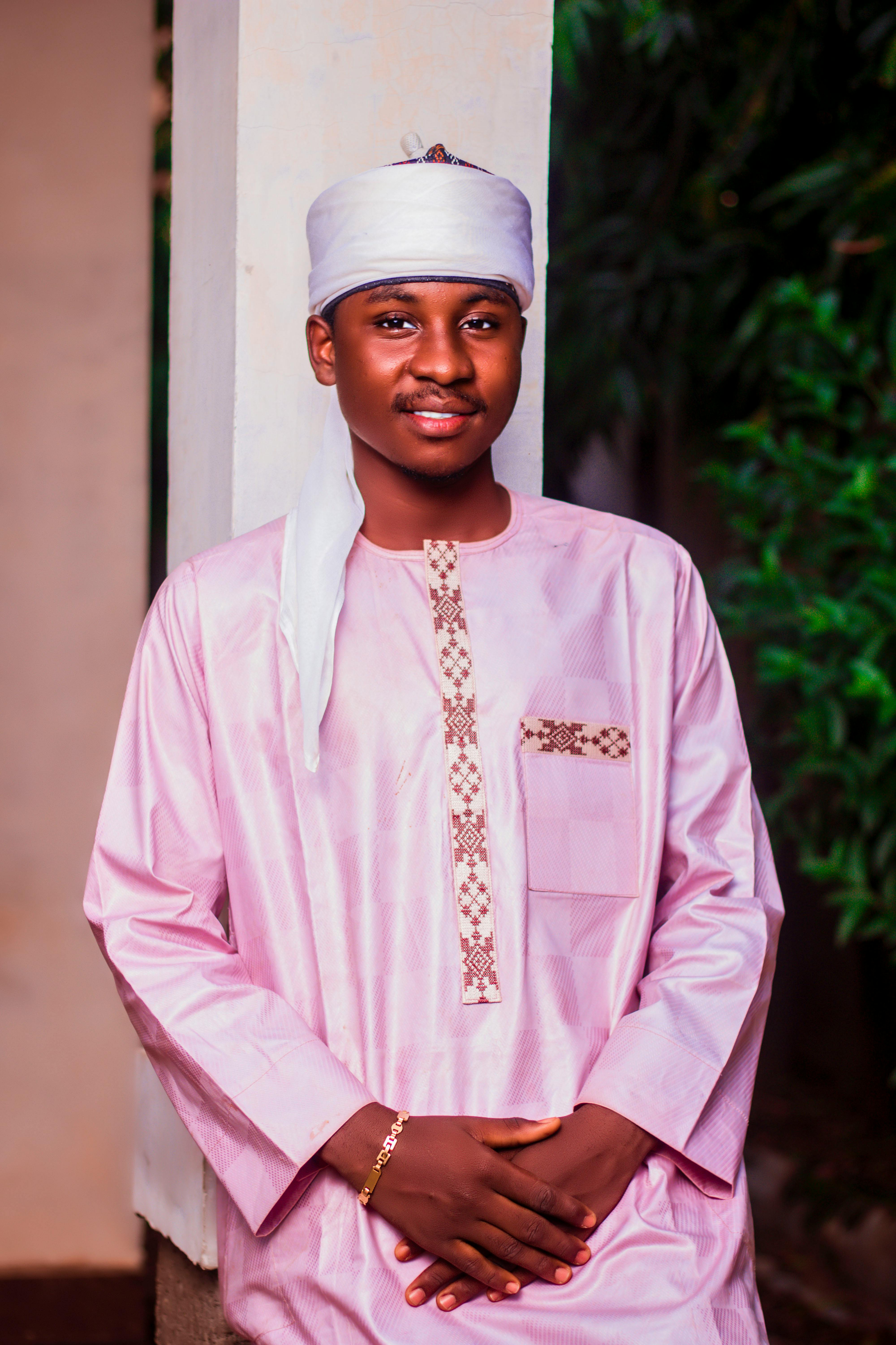 Portrait of a young man in traditional attire with a serene expression, taken outdoors.