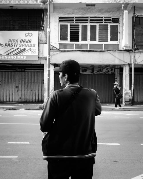 Free A man stands on a city street, observing the surroundings in monochrome. Stock Photo