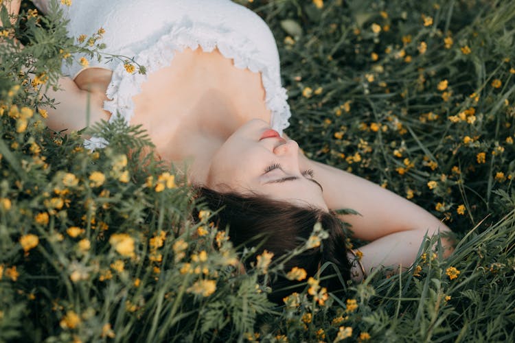 Woman Wearing White Dress Lying On Flower Field