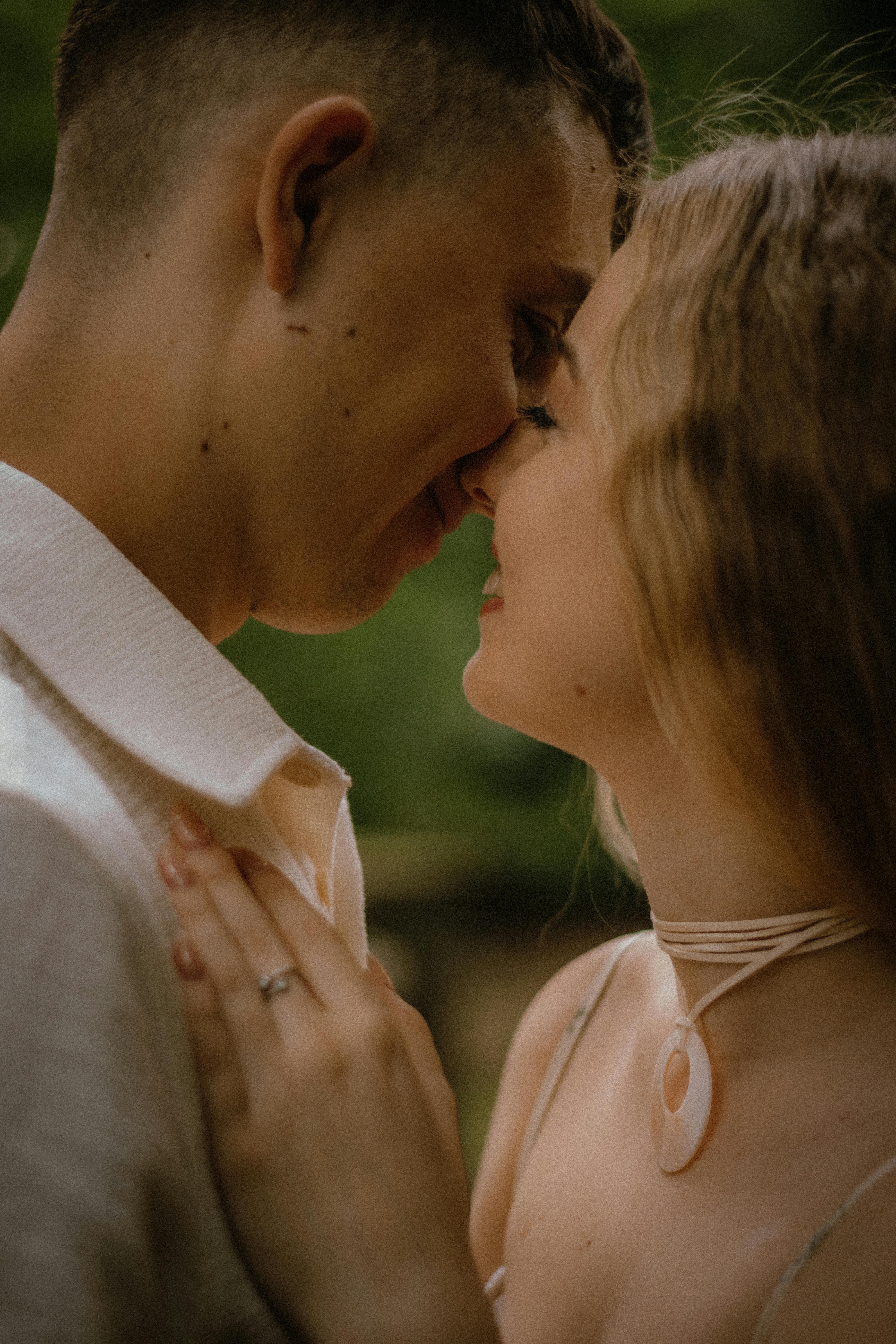 Close intimate moment of couple face to face in soft embrace, exuding warmth, love, and deep connection under moody light