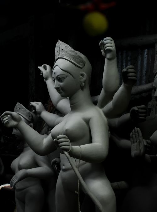 Free Clay sculpture of a Hindu goddess captured in a dark, atmospheric setting, showcasing intricate artistry. Stock Photo