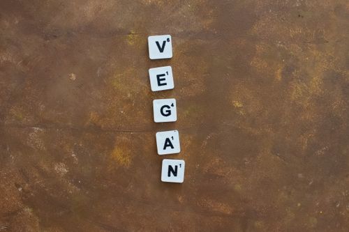 Free A creative arrangement of Scrabble tiles spelling 'Vegan' on a rustic brown background, emphasizing a plant-based lifestyle. Stock Photo