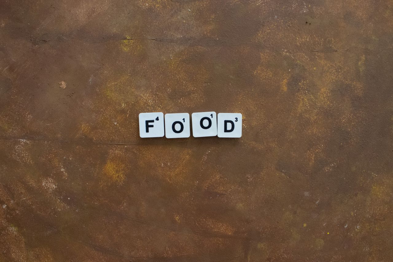 scrabble tiles spelling food on a textured brown surface ideal for cul
