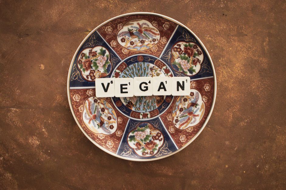 Artistic plate with 'VEGAN' text, promoting plant-based lifestyle.