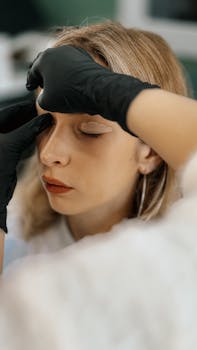 Makeup artist expertly applies eyeliner to relaxed woman in salon setting.