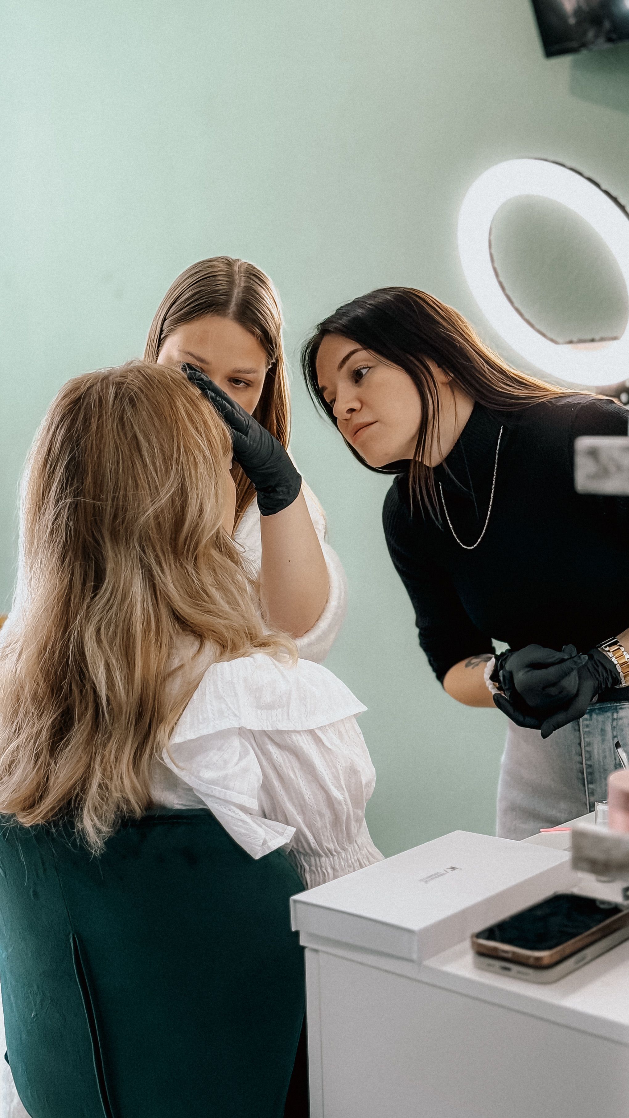 gratis Twee visagisten brengen cosmetica aan op een klant in een schoonheidssalon onder ringlicht. Stockfoto