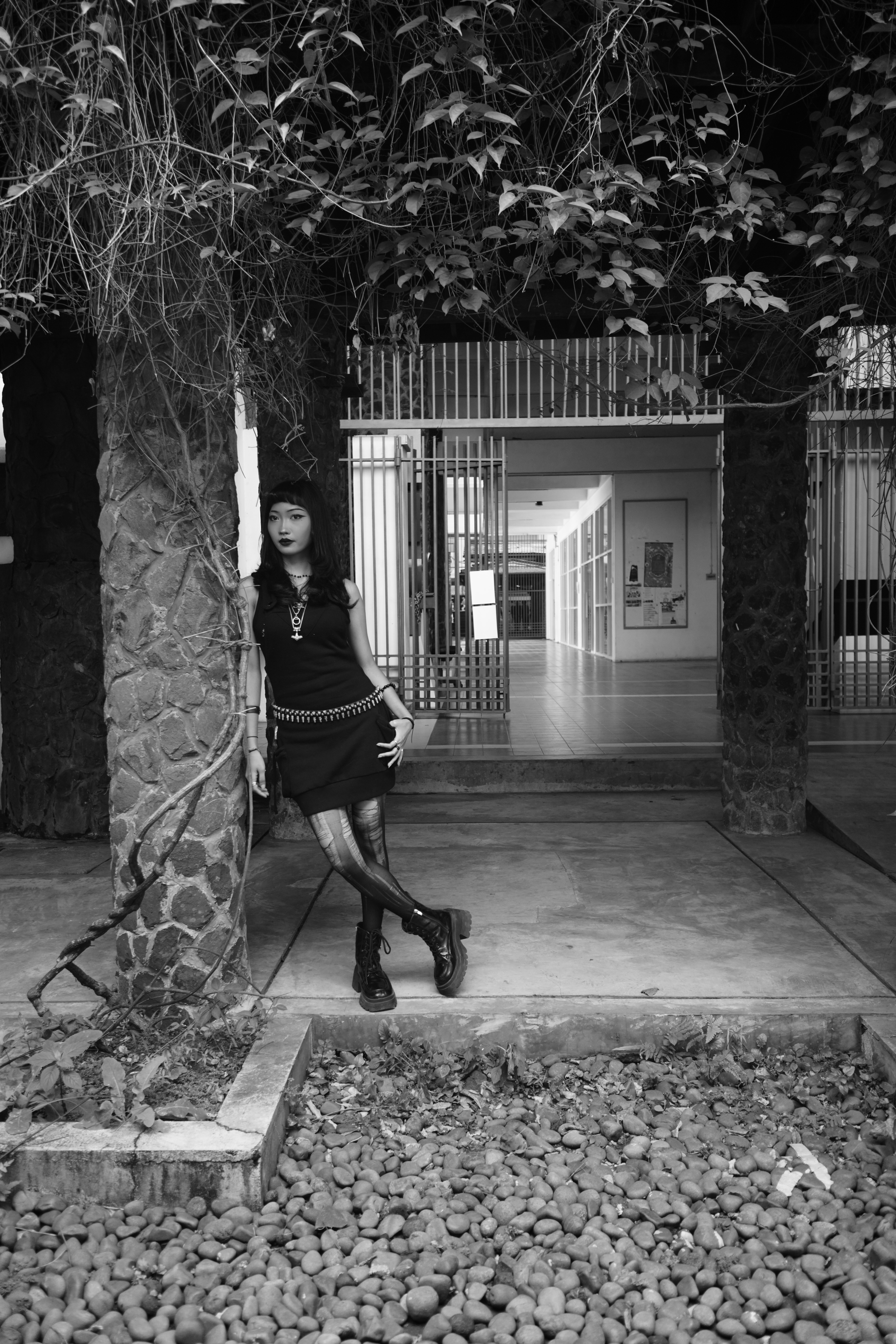 Black and white portrait of a goth woman posing in an architectural urban environment.