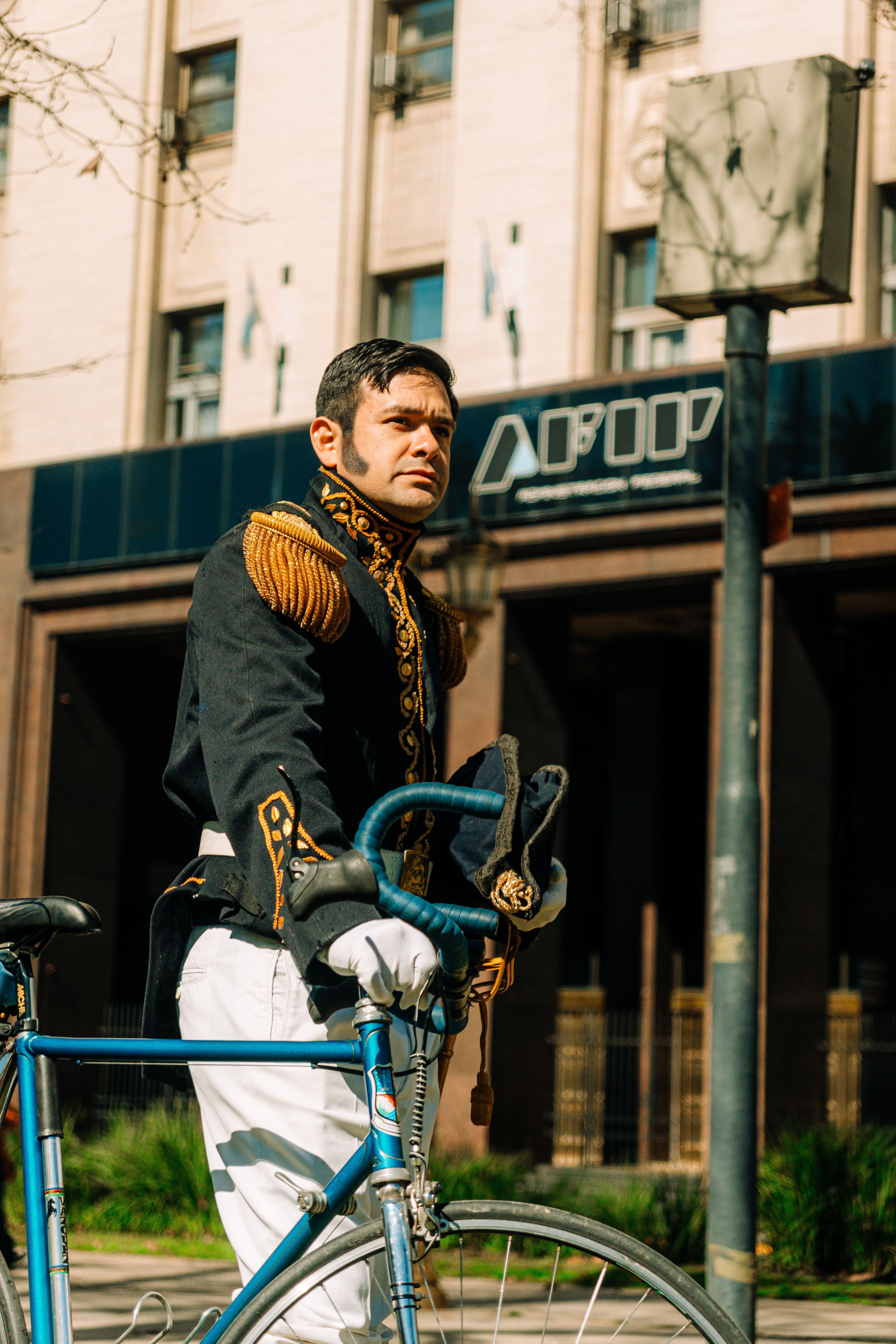 Person in historical attire poses with a bicycle on a street in Buenos Aires, Argentina.
