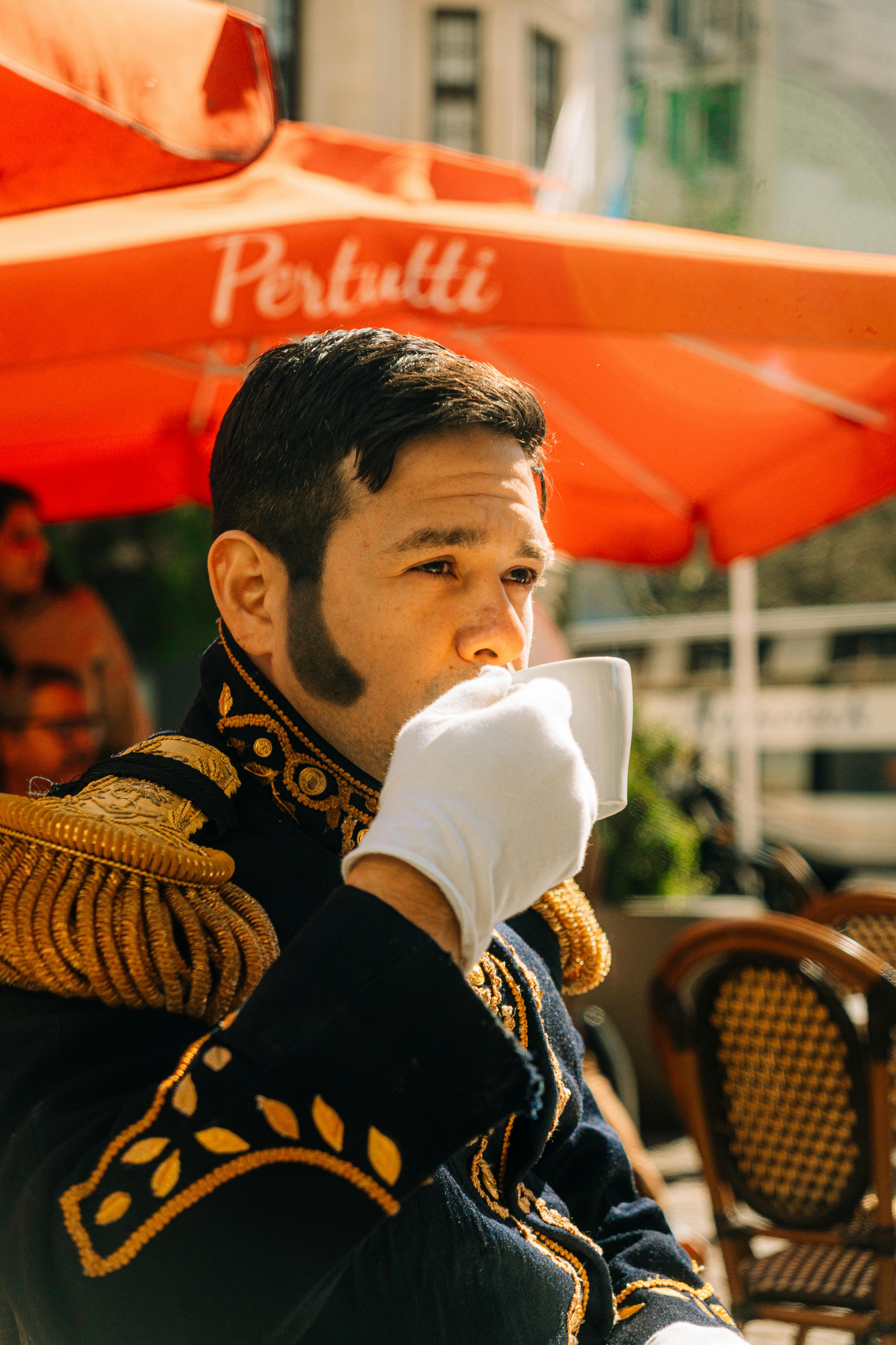 Man in historic costume drinks coffee outside a cafe in Buenos Aires, Argentina.