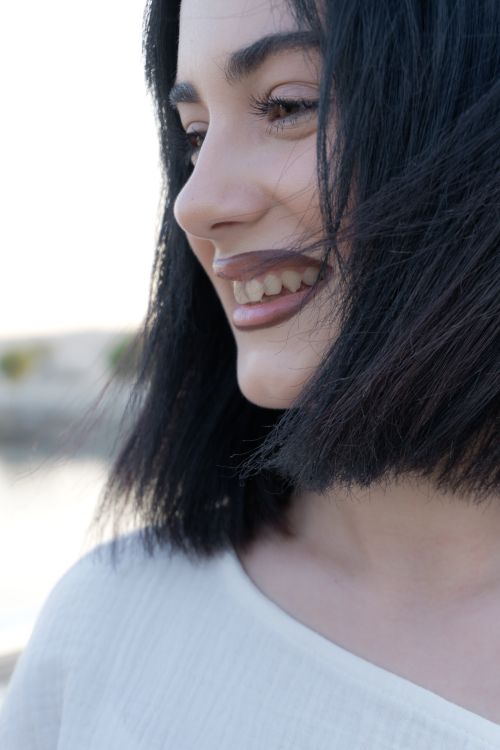 Free Close-up of a smiling young woman with black hair enjoying the outdoors, exuding happiness and positivity. Stock Photo