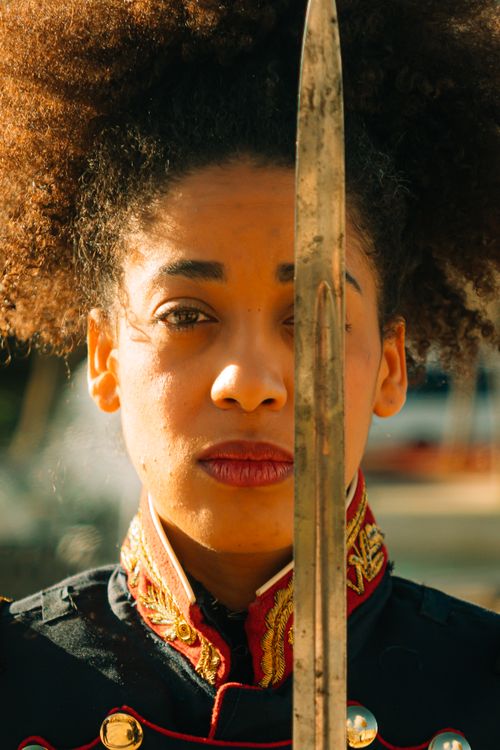 Free Close-up portrait of a woman in ornate military uniform holding a sword outdoors. Stock Photo
