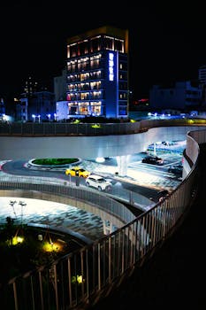 Brightly lit urban street with modern architecture and traffic in Taiwan at night, showcasing vibrant city life.