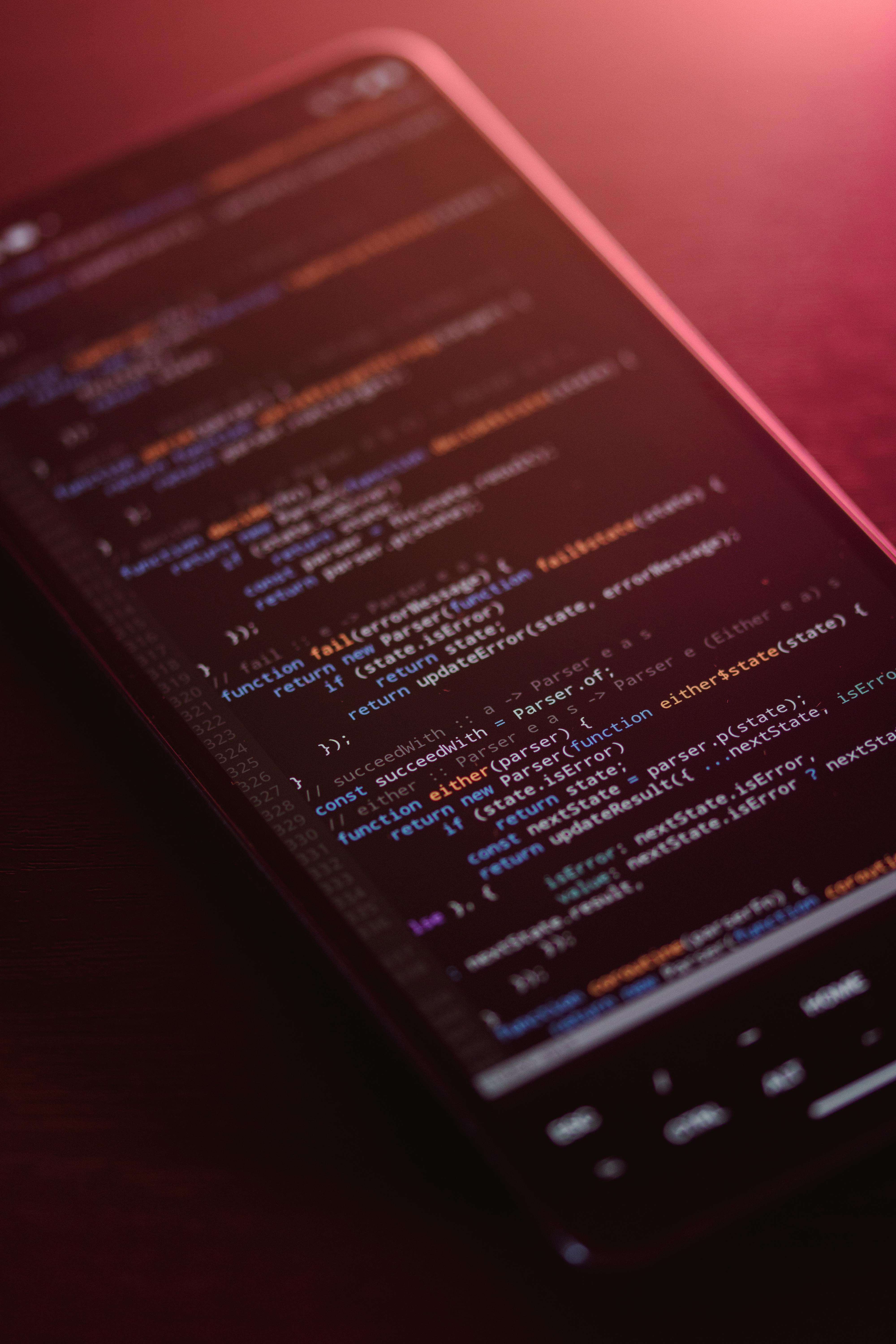 Free Colorful code displayed on a smartphone screen with a warm glow. Stock Photo