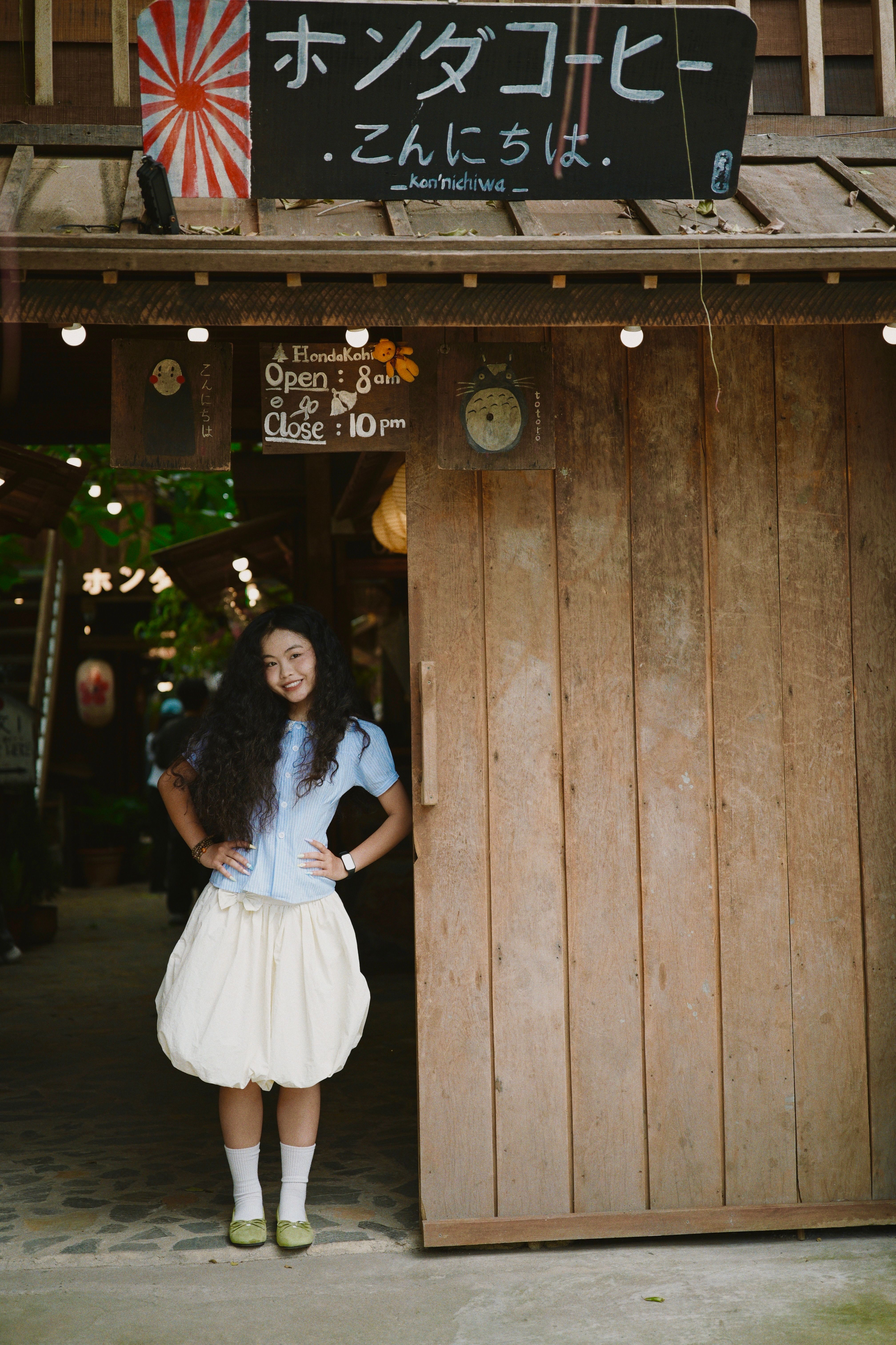 Smiling woman standing at a cozy coffee shop entrance, showcasing charm.