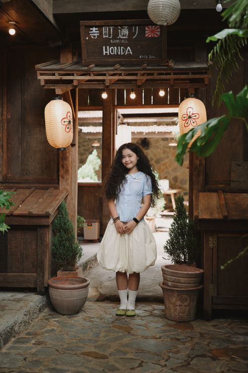 Free A young girl stands in an inviting wooden entryway adorned with lanterns. Stock Photo