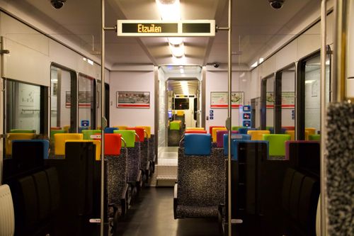Interno moderno di un treno con sedili colorati su un servizio ferroviario svizzero.
