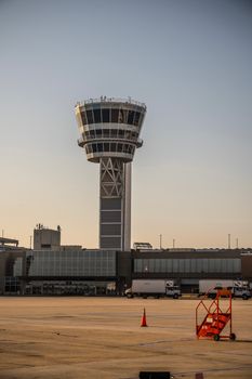 A modern airport control tower bathed in sunset light, capturing an airfield's serene evening atmosphere.