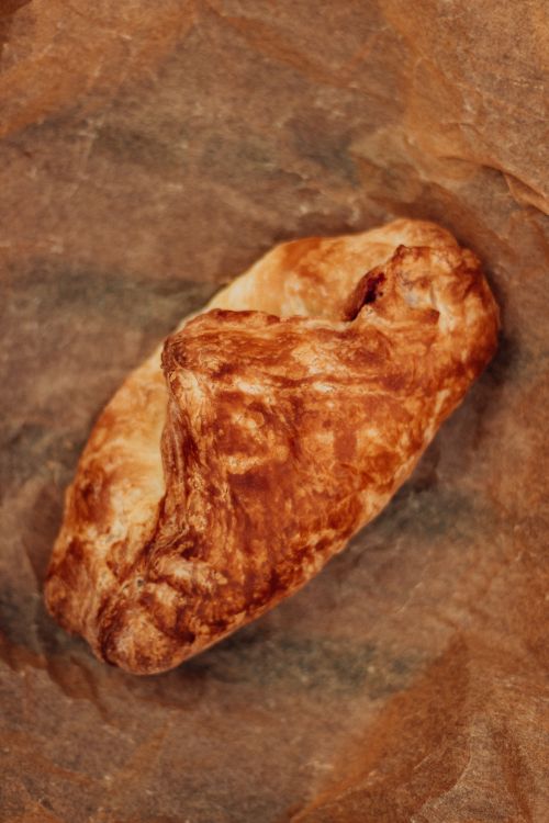 Free Close-up of a golden brown baked pastry on parchment, showcasing its crisp texture. Stock Photo