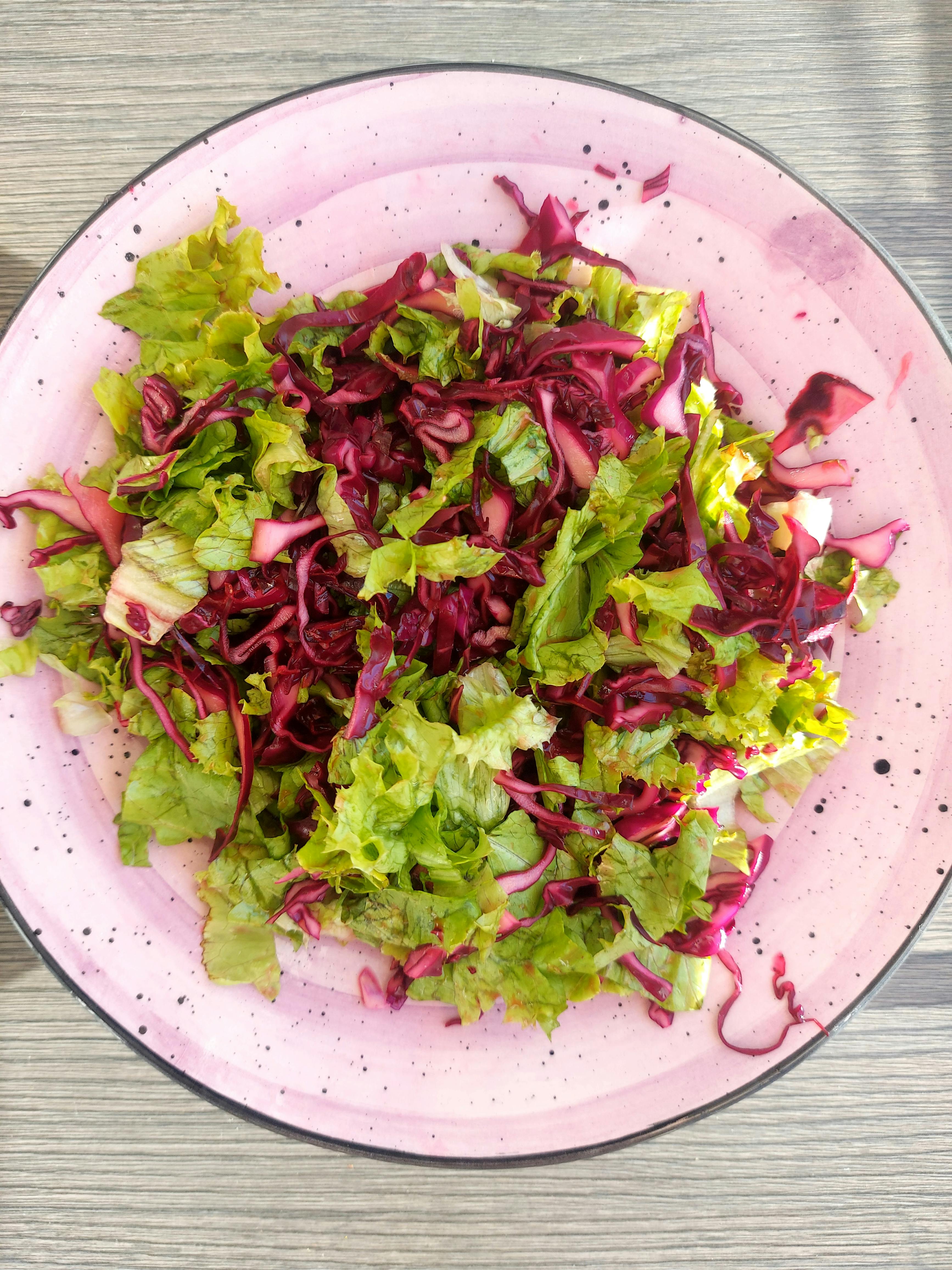 Insalata mista con verdure e cavolo rosso su piatto rosa