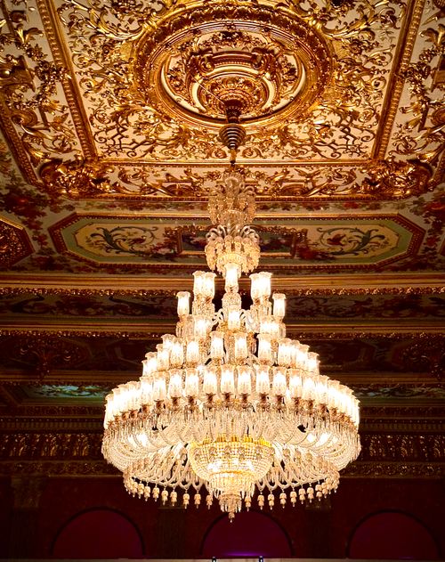 Free Stunning crystal chandelier hanging from an ornately decorated ceiling. Stock Photo
