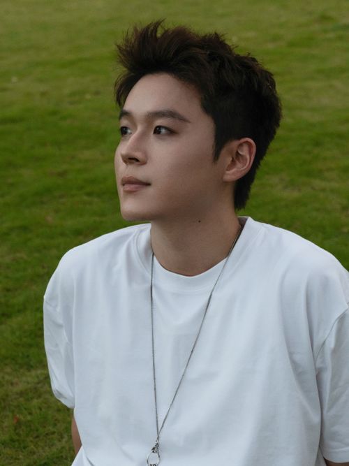 Free Portrait of a young man sitting outdoors in a park with green grass. Stock Photo