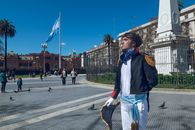 A man dressed as an Argentine historical figure in Plaza de Mayo, Buenos Aires, with the iconic Casa Rosada in the background.