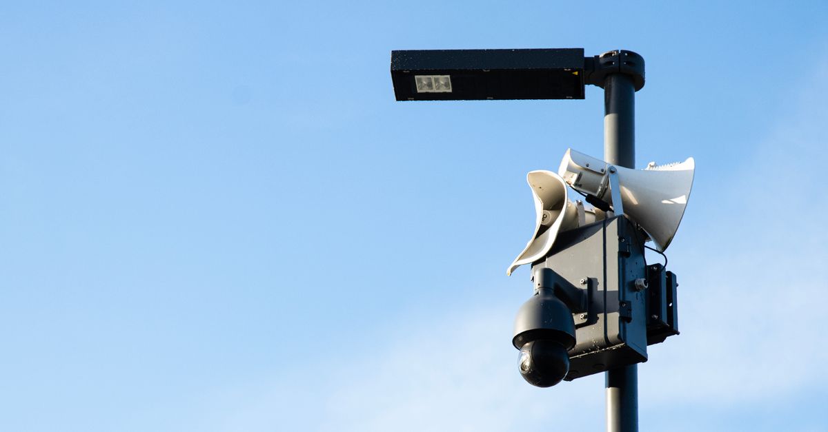 Street lamp post with security camera and speakers under a blue sky in Jūrmala, Latvia.