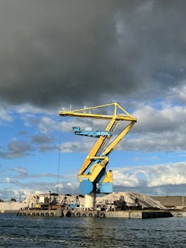 A large yellow industrial crane at Amsterdam harbor against a stormy sky, showcasing shipping and construction themes.