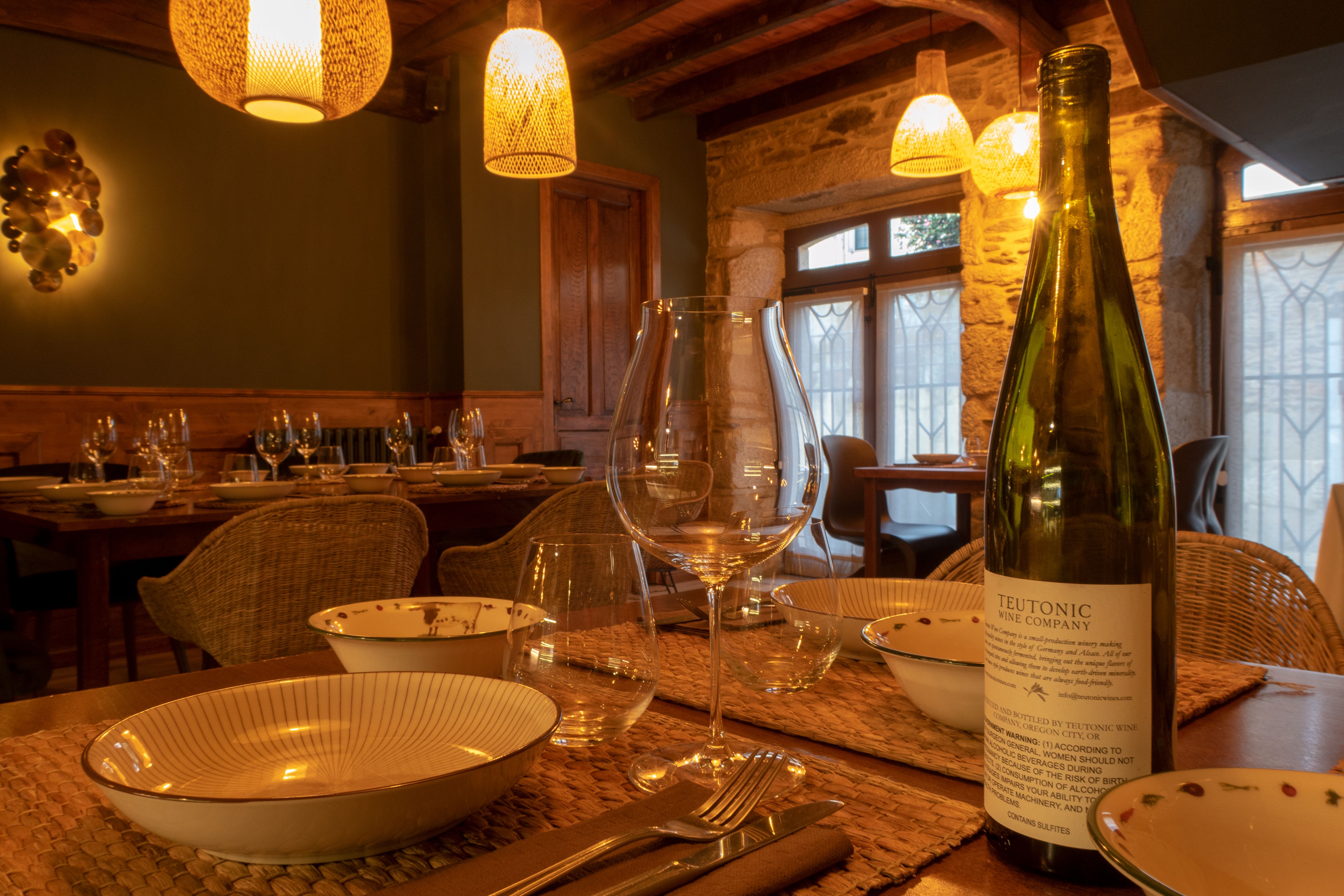 Tavola apparecchiata in stile rustico con vino e stoviglie, in una sala accogliente