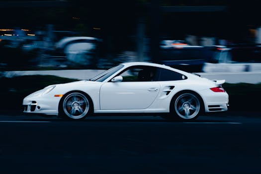 Dynamic shot of a white sports car driving fast on a city street at night, showcasing speed and style.