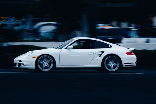 Free Dynamic shot of a white sports car driving fast on a city street at night, showcasing speed and style. Stock Photo