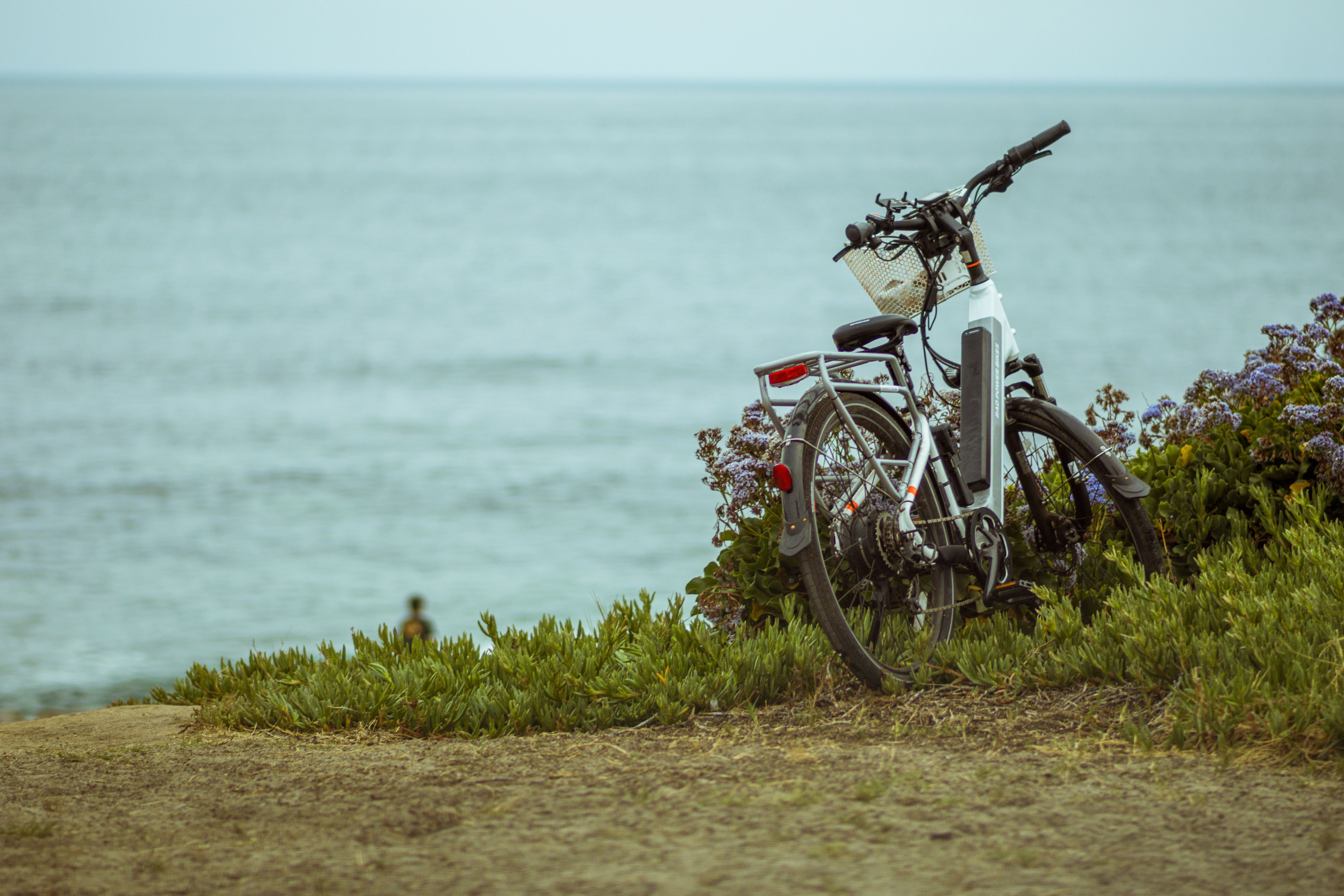 Electric bike parked alone on a grassy cliff overlooking the ocean.