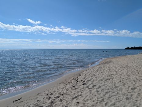 A tranquil beach scene with clear blue skies and gentle waves lapping the shore.