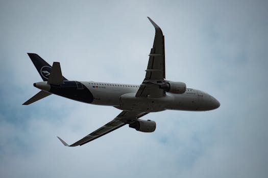 A view of a Lufthansa airplane flying through cloudy skies at Munich Airport.
