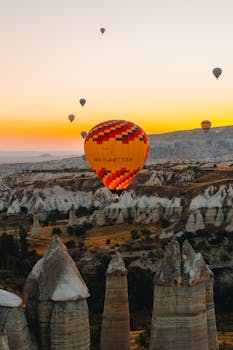 Colorful hot air balloons floating over Cappadocia's rock formations at sunrise.