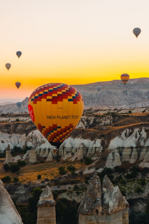 Free Vibrant hot air balloons float over the unique rock formations of Cappadocia, Türkiye at sunrise. Stock Photo
