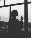 城市背景的窗户捕捉到一个女人吸烟的喜怒无常的黑白剪影