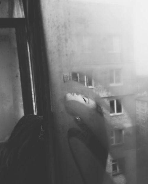 Free Black and white portrait of a woman with closed eyes reflected in a window, evoking a moody atmosphere. Stock Photo