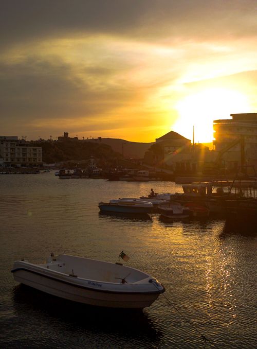 Free Tranquil harbor scene at sunset with boats reflecting on the water, creating a peaceful atmosphere. Stock Photo