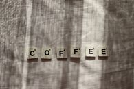 Scrabble tiles spelling 'coffee' with light and shadow on fabric surface. Perfect for coffee and word lovers.