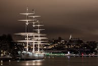 一艘雄伟的发光帆船停泊在斯德哥尔摩港的夜晚，映衬着美丽的城市灯光