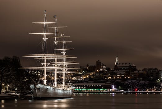一艘雄伟的发光帆船停泊在斯德哥尔摩港的夜晚，映衬着美丽的城市灯光